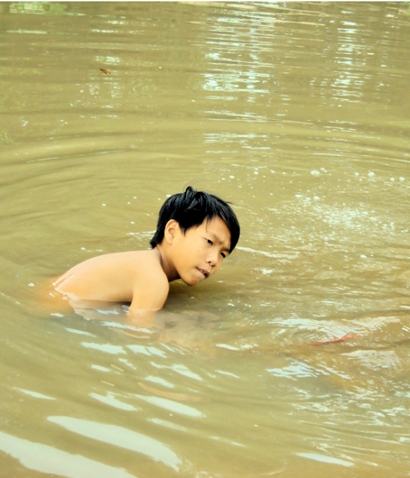 Em Phan Văn Cao đang cố gắng mò những con hến nằm sâu dưới bùn, cát.