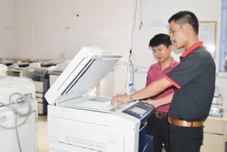 Ông Phạm Công Sơn (bên phải) kiểm tra hoạt động của một chiếc máy photocopy mới chuẩn bị giao cho khách.  Ảnh: V. nam