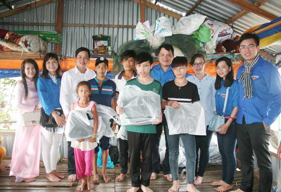 Thành viên trong đoàn tặng quà cho các em học sinh nghèo tại khu vực làng bè xã Phú Ngọc, huyện Định Quán.