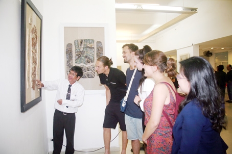 Thầy Nguyễn Quang Hoàng đang giới thiệu một tác phẩm tranh gốm trong triển lãm tranh gốm chủ đề Chiều đối diện cho một nhóm du khách nước ngoài ở khu trưng bày tại Hội Mỹ thuật TP.Hồ Chí Minh (218A, Pasteus, phường 6, quận 3, TP.Hồ Chí Minh).