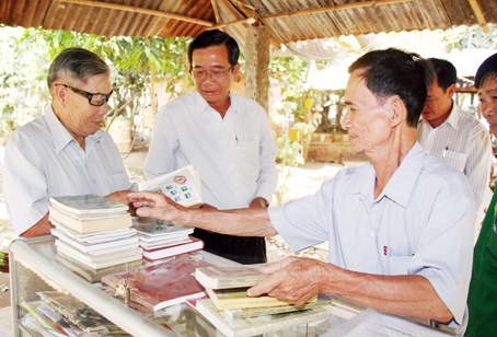  Giám đốc Thư viện Đồng Nai Nguyễn Văn Tám (giữa) trao đổi cùng người dân về một cuốn sách tại tủ sách miễn phí phục vụ cộng đồng ở Khu giải trí người cao tuổi (ấp Tân Bình 2, xã Lang Minh, huyện Xuân Lộc) của ông Lê Nuôi. Ảnh: V.TRUYÊN