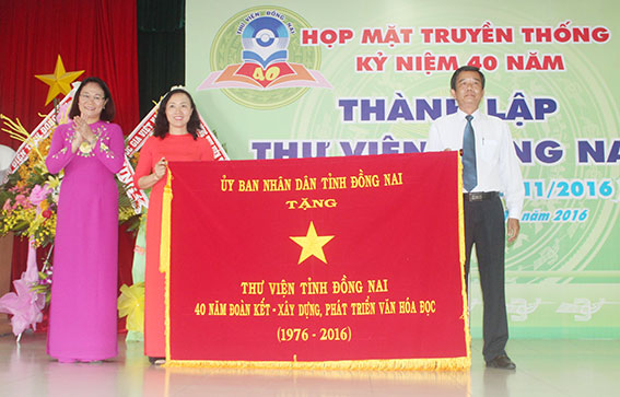  Bà Đặng Thanh Thủy, Trưởng ban Thi đua - khen thưởng tỉnh trao bức trướng của UBND tỉnh cho đại diện Thư viện tỉnh với nội dung “Thư viện tỉnh Đồng Nai: 40 năm đoàn kết – xây dựng, phát triển văn hóa đọc”