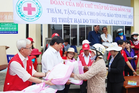 Ông Nguyễn Văn Xuân (bìa trái), Phó chủ tịch thường trực Hội Chữ thập đỏ tỉnh, trao quà cho đồng bào miền Trung. Ảnh: Hội Chữ thập đỏ tỉnh cung cấp