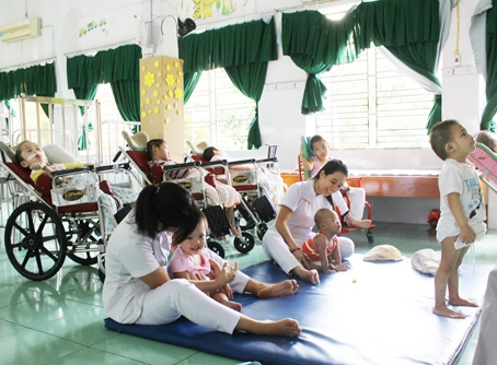 Nhân viên Trung tâm nuôi dưỡng trẻ khuyết tật tỉnh chăm sóc trẻ khuyết tật. Ảnh: N.T.Luân