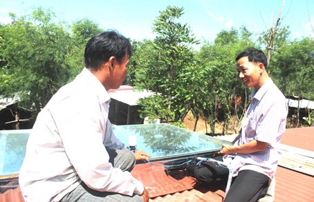 Ông Nguyễn Văn Anh (bìa phải) đang hướng dẫn khách hàng sử dụng bể đun nước nóng bằng năng lượng mặt trời.