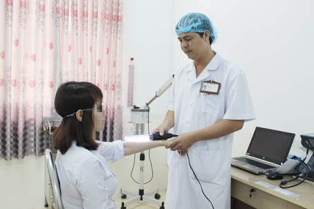 Bác sĩ Đặng Ngọc Toàn đang chiếu đèn điều trị bệnh bạch biến cho một bệnh nhân. Ảnh: T.Anh