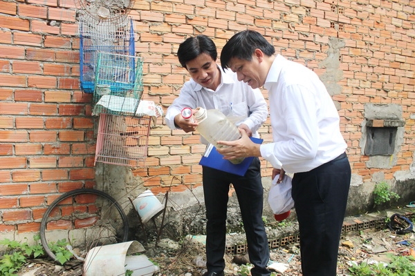 Thứ trưởng Bộ Y tế Nguyễn Thanh Long (bên phải) giám sát mật độ lăng quăng tại một khu vườn nhà người dân ở phường Long Bình, TP.Biên Hòa. Ảnh: Ngọc Thư.