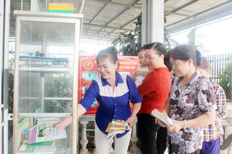 Các thành viên Câu lạc bộ gia đình phát triển bền vững ở xã Sông Trầu (huyện Trảng Bom) tìm đọc sách về hôn nhân gia đình, khuyến nông trong khi chờ các thành viên đến đủ để sinh hoạt.