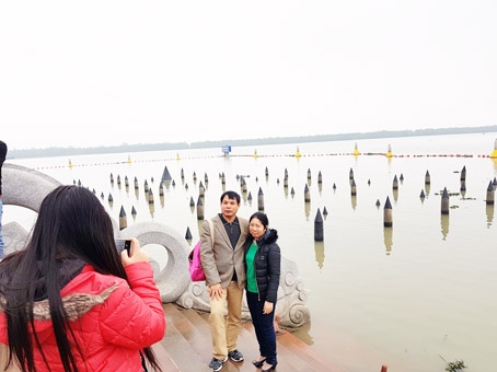 Du khách chụp hình lưu niệm bên bãi cọc mô phỏng lại bãi cọc Bạch Đằng năm xưa trong Khu di tích Bạch Đằng Giang.