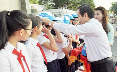 Ông Trịnh Tuấn Liêm, Giám đốc Sở Giao thông - vận tải, Phó ban thường trực Ban An toàn giao thông tỉnh tặng mũ bảo hiểm cho học sinh tại Lễ ra quân năm an toàn giao thông 2017.   ảnh: THANH HẢI