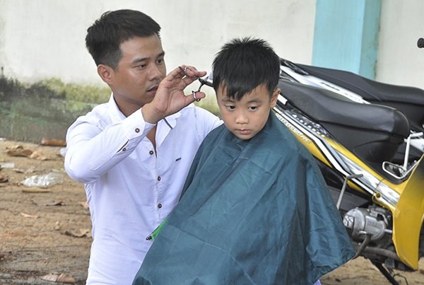 Nhóm bạn trẻ đang cắt tóc miễn phí tại một trường học ở phường Long Bình (TP.Biên Hòa).