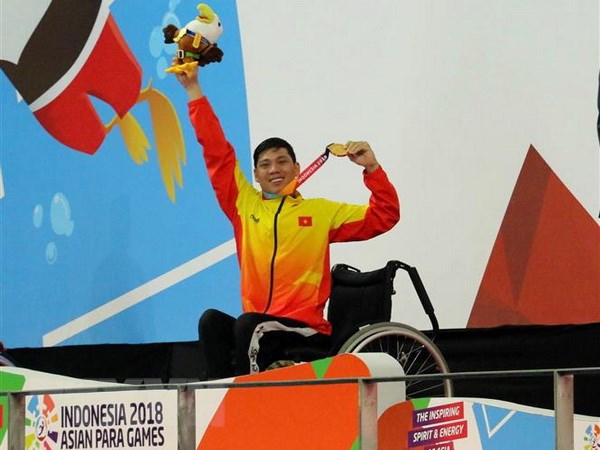 Vận động viên Võ Thanh Tùng tự hào giơ cao tấm Huy chương vàng thứ 3 tại Asian Para Games 2018. (Ảnh: Hải Ngọc/TTXVN)