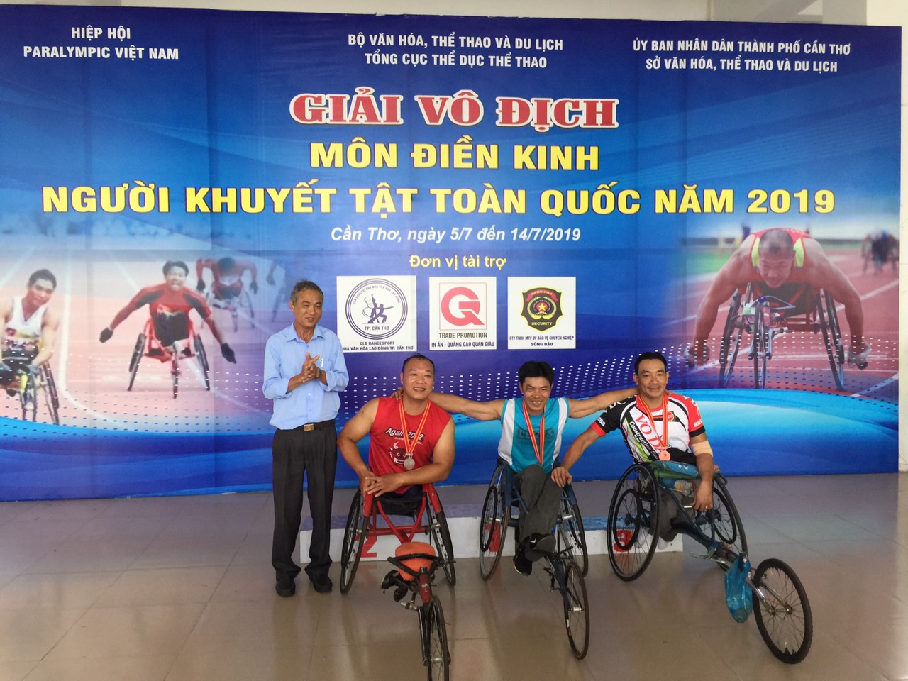 Hai VĐV Nguyễn Văn Bích (giữa, áo xanh) và Nguyễn Kiên (bìa phải) nhận HCV, HCĐ cự ly 400m xe lăn hạng thương tật T53/54.