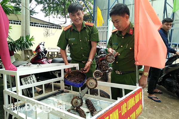 Trung tá Đặng Xuân Kiên (bìa phải), Trưởng Công an phường Tam Phước (TP.Biên Hòa) với mô hình xe hút đinh của Công an phường .