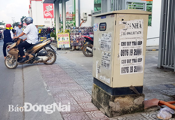 Một bốt điện trên vỉa hè đường Nguyễn Ái Quốc, đoạn gần nút giao thông Tân Phong bị các tờ rơi quảng cáo “bủa vây”