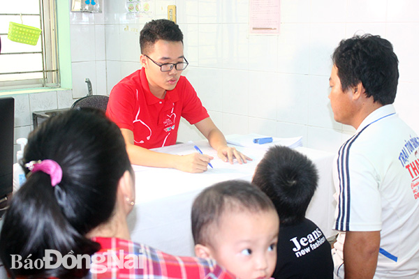 Anh Nguyễn Văn Hiểu (phường Tân Phong, TP.Biên Hòa) được thành viên Ban tổ chức chương trình Trái tim cho em hướng dẫn về làm thủ tục để xin được chương trình hỗ trợ phẫu thuật tim miễn phí cho con. (ảnh: H.Dung)
