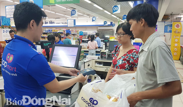 Người dân sử dụng hình thức thanh toán không dùng tiền mặt khi mua sắm tại Co.opmart Biên Hòa. Ảnh: H.Quân