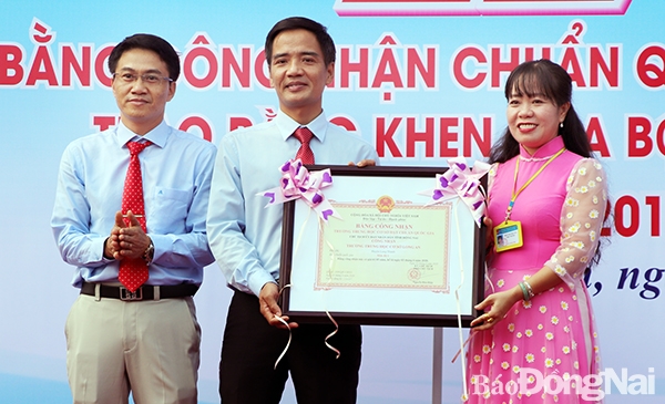 Ông Đỗ Huy Khánh, Phó giám đốc sở GD-ĐT Đồng Nai trao Bằng công nhận trường đạt chuẩn quốc gia cho đại diện Ban giám hiệu Trường THCS Long An