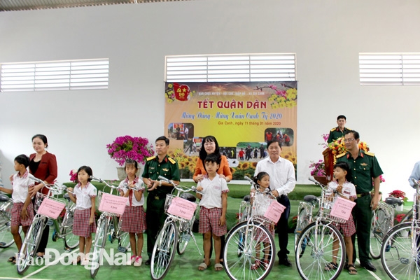 Lãnh đạo H.Định Quán tặng quà và trao xe đạp cho học sinh nghèo vượt khó trong Tết quân dân năm 2020. Ảnh: N. Anh