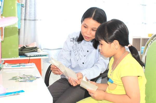 Chị Phạm Thị Tú Hương, ở xã Đại Phước (H.Nhơn Trạch) cùng con gái xem lại ảnh mỗi khi nhớ cha. Ảnh: N.Sơn