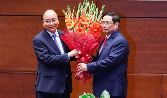 Chủ tịch nước Nguyễn Xuân Phúc tặng hoa chúc mừng Thủ tướng Phạm Minh Chính. Ảnh VGP Nhật Bắc
