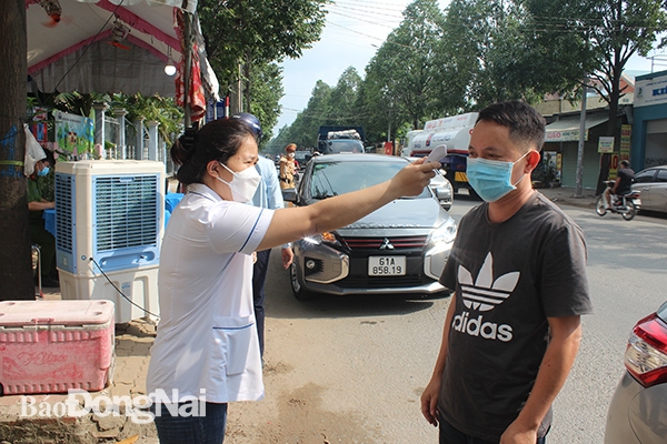 Nhân viên Y tế đo thân nhiệt người dân đi đường tại một chốt trực được UBND thành phố Biên Hòa thành lập tại phường Tân Hạnh