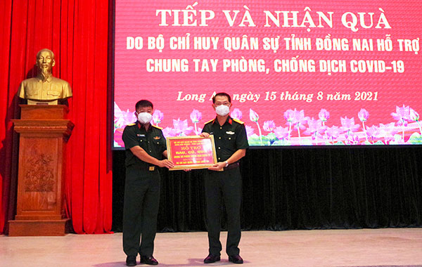 Bộ CHQS tỉnh Long An tiếp nhận bảng tượng trưng hỗ trợ rau củ quả của Bộ CHQS tỉnh Đồng Nai. Ảnh: Biện Cường
