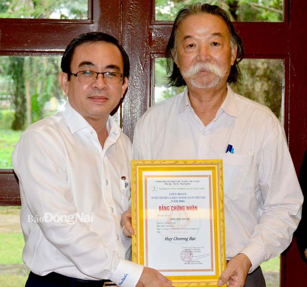 Nhạc sĩ Hoàng Lương (phải) vinh dự nhận huy chương bạc Liên hoan Tuyên truyền ca khúc ngành cao su Việt Nam năm 2021. Ảnh: NVCC