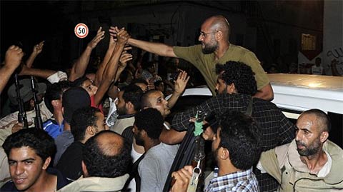 Trông tự tin và thoải mái, con trai Saif al-Islam của Gaddafi chào hỏi những người ủng hộ ở Tripoli, một ngày sau khi quân nổi dậy tuyên bố họ đã bắt giữ được ông này. Saif tuyên bố chính phủ của cha mình đã "bẻ gãy xương sống" của quân nổi dậy và họ đang giành chiến thắng. (Ảnh: Reuters)