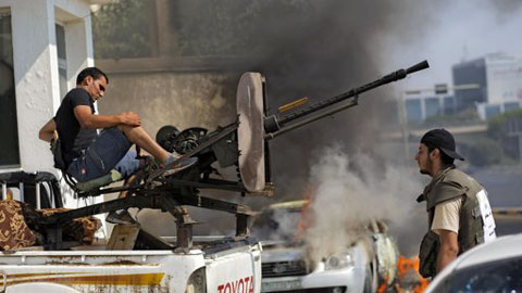 Xe hơi bốc cháy và súng vẫn nổ khi các chiến binh nổi dậy ở Tripoli tiếp tục cuộc chiến chống lực lượng Gaddafi. (Ảnh: AP)