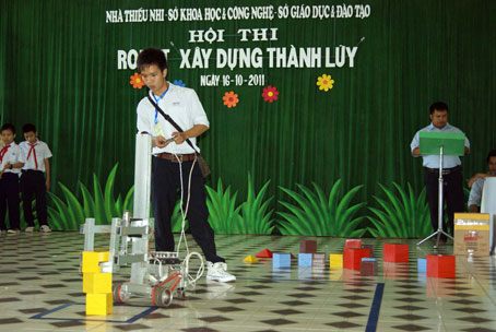 Em Lý Anh Huy thực hiện phần thi điều khiển Robot xây dựng thành lũy