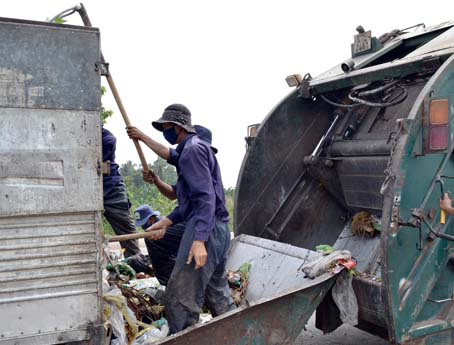 Công nhân Xí nghiệp môi trường Biên Hòa đang chuyển rác thu gom từ các hộ và xe chuyên dụng.  Ảnh: V.N