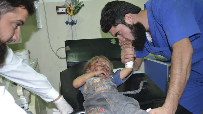 Bác sĩ hôn tay một cậu bé bị thương trong trận nã pháo của quân đội Syria hôm 28-9 - Ảnh: Reuters