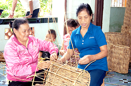 Bà Đinh Thị Xuân (phải) hướng dẫn hội viên đan các sản phẩm từ lục bình khô.