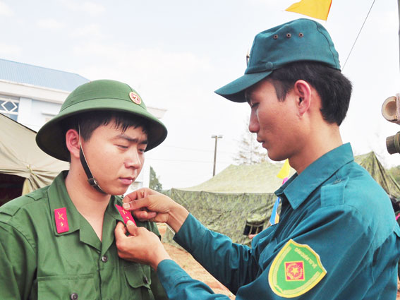 Anh Lê Quốc Khởi, phó chỉ huy trưởng Ban CHQS xã Xuân Bảo chỉnh trang quân phục cho tân binh Nguyễn Việt Anh.