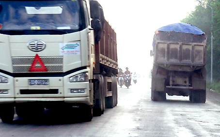 Tình trạng xe quá tải (bên trái là xe chở bauxite, bên phải xe tải ben) vẫn thường xuyên lưu thông trên quốc lộ 20. Các xe quá tải này phá tan nát mặt đường cũ, làm mau hư mặt đường vừa được nâng cấp mở rộng (ảnh chụp ngày 18-4).