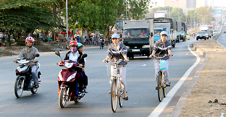 Xe đạp và xe máy dàn hàng tư trên làn đường xe khách và xe tải, xe container ở quốc lộ 1 đi qua ngã tư Bồn Nước (phường An Bình).