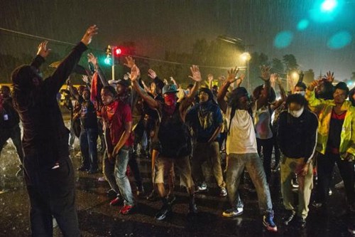  Những người biểu tình đứng tụ tập ngay giữa một con đường trung tâm Ferguson bất chấp lệnh giới nghiêm của chính phủ.
