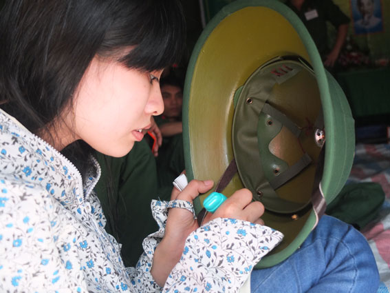 Cô bé Nguyễn Thị Thanh khắc kỹ niệm trên mũ bộ đội cho anh trai Nguyễn Anh Quân (ấp 8, xã Gia Canh).