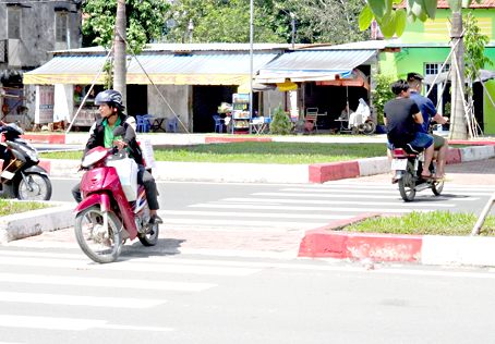 Người chạy xe 2 bánh chạy qua lại trên đường dành cho người đi bộ dưới chân cầu Hóa An mới (phía Biên Hòa) gây nguy hiểm cho các xe đang đổ dốc cầu.