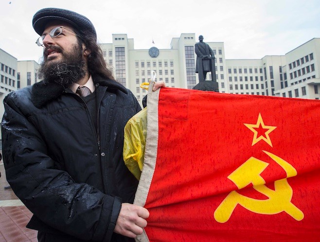 Một người cầm lá cờ Xô Viết đứng trước tượng đài Lenin ở Minsk, Belarus (Nguồn: Reuters)
