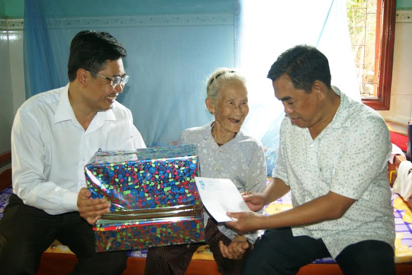 Các đồng chí: Huỳnh Văn Tới, Trưởng ban Tuyên giáo Tỉnh ủy (phải) và Viên Hồng Tiến, Phó ban thường trực Ban dân vận Tỉnh ủy (trái) tặng quà Mẹ Việt Nam anh hùng