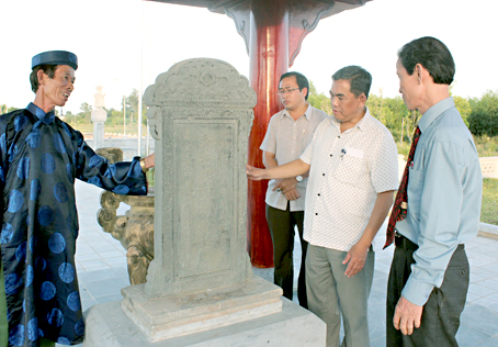 Ông Nguyễn Hữu Tiến (bìa trái), hậu duệ dòng họ Nguyễn Hữu giới thiệu tấm mộ bia Lễ Thành hầu Nguyễn Hữu Cảnh sau khi cải táng từ Đồng Nai về.
