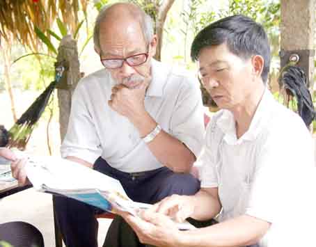 Các nhà thơ nghiệp dư Lê Nuôi (bên phải)  và Trần Đình Thanh ngụ xã Lang Minh, huyện Xuân Lộc đang bình luận một bài thơ đăng trên báo. Ảnh: V.TRUYÊN