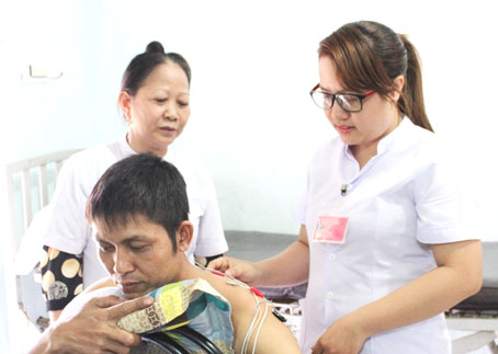 Điều dưỡng Phạm Thị Thái (bìa phải) hướng dẫn nhân viên châm cứu cho bệnh nhân. Ảnh: N.Thư