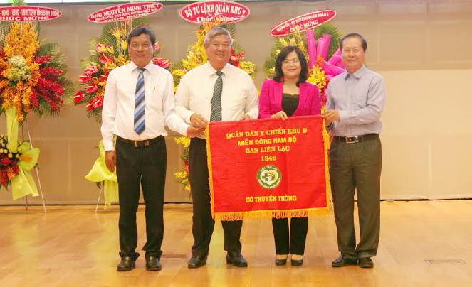 Phó chủ tịch UBND tỉnh Nguyễn Hòa Hiệp (thứ hai từ phải qua) nhận cờ truyền thống đăng cai tổ chức họp mặt Quân dân y Chiến khu Đ lần thứ 28 vào năm 2017.