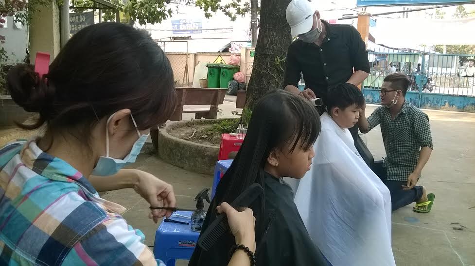 Các nhân viên của tiệm cắt tóc Salon Nguyễn đang cắt tóc miễn phí cho học sinh