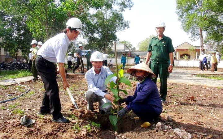 Chủ tịch UBND huyện Ngô Thế Ân (cầm xẻng)  đang cùng trồng cây với cán bộ, nhân viên các cơ quan, đơn  vị