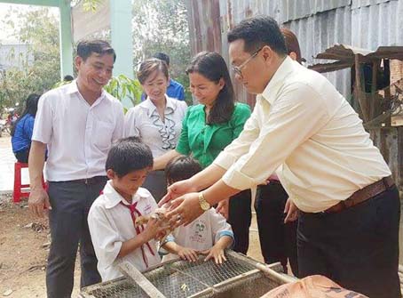 Phó giám đốc Nhà thiếu nhi Đồng Nai Trương Hải Thi (bìa phải) trao đàn gà Khăn quàng đỏ cho em Nguyễn Văn Triệu (huyện Định Quán).