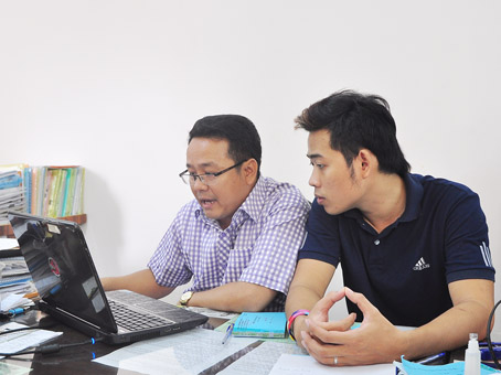 Ông Trương Hải Thi (trái) trao đổi nội dung bài viết với nhân viên trẻ của Nhà thiếu nhi Đồng Nai.